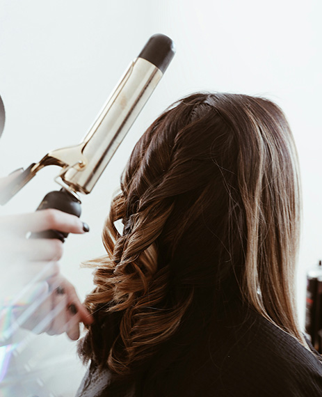 Estilista realizando ondas en el cabello utilizando una plancha de pelo durante un curso de peluquería.