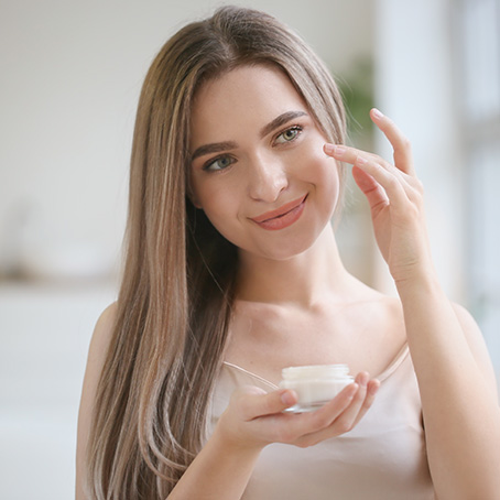 Mujer aplicandose crema hidratante en la mejilla