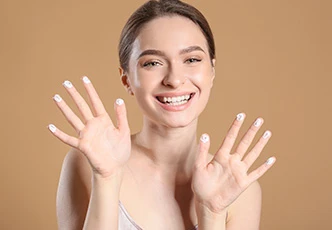 Mujer sonriendo con crema facial en las manos para una rutina con acné