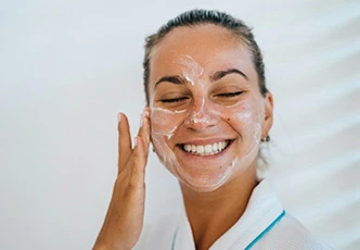Mujer aplicándose crema hidratante en la cara para una rutina facial anti envejecimiento
